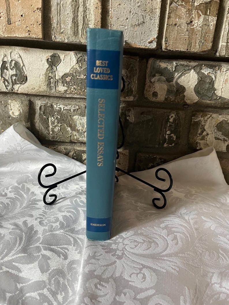 May include: A blue hardcover book titled "Selected Essays" by Emerson. The book is part of the "Best Loved Classics" series.