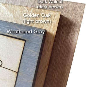 May include: A close-up of three wooden samples: Dark Walnut (dark brown), Golden Oak (light brown), and Weathered Grey. The samples are layered, displaying the different wood grain patterns and colour variations. Text labels identify each wood type.