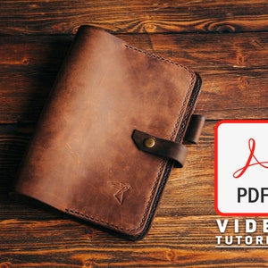 May include: A brown leather notebook cover with a brass button closure and a stitched design. The cover is on a wooden surface with a PDF icon and the text "VIDEO TUTORIAL".