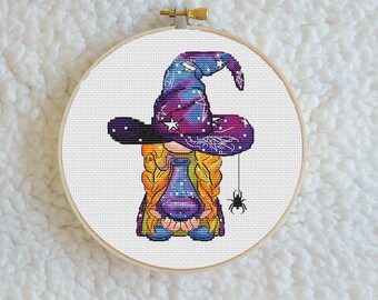 Può includere: Uno schema di punto croce di una strega con un cappello a tema galassia viola e blu, che tiene una bottiglia di pozione e un ragno su una corda.