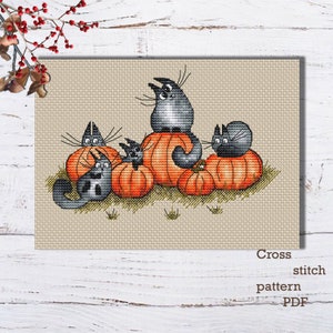May include: Cross stitch pattern PDF of five gray cats sitting on orange pumpkins. The cats are all looking in different directions. The pumpkins are stacked on top of each other.