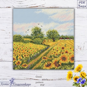 Może przedstawiać: Wzór do haftu krzyżykowego PDF przedstawiający wiejski krajobraz z polem słoneczników, polną drogą prowadzącą do małej wioski w oddali i błękitnym niebem z białymi chmurami.