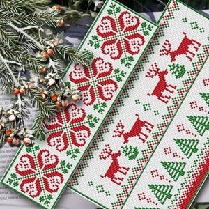 Op de afbeelding: Drie rode en groene geborduurde bladwijzers met verschillende ontwerpen. De eerste bladwijzer heeft een sneeuwvlokkenpatroon, de tweede een rendierpatroon en de derde een kerstboompatroon.