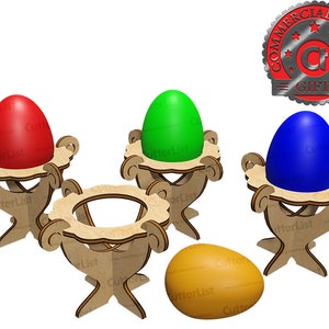 以下が含まれることがあります： 装飾的な切り抜きのある木製のエッグホルダー。それぞれ赤、緑、青の鮮やかな色の卵が入っています。4つ目の卵は黄色です。ホルダーは明るい色の木材で作られています。商用ライセンスギフトバッジが右上隅にあります。