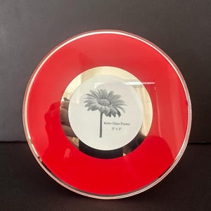 May include: A round, red retro glass frame with a gold-colored inner rim. The frame holds a black and white floral print. The text "Retro Glass Frame 3" x 3"" is visible on the print. The frame is approximately 3 inches in diameter.