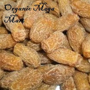 Puede incluir: Primer plano de un montón de dátiles secos, mostrando su piel arrugada y marrón dorada. La imagen presenta el texto "Organic Mega Mart" en cursiva, sugiriendo productos alimenticios orgánicos.