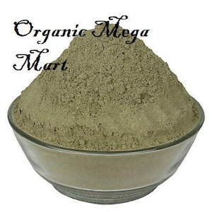 Op de afbeelding: Een heldere glazen kom gevuld met een berg lichtgroen poeder. De tekst "Organic Mega Mart" staat in zwart cursief boven de kom geschreven. Het poeder heeft een fijne, korrelige textuur.