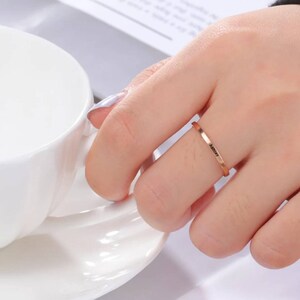 Może przedstawiać: Cienki złoty pierścionek z grawerem "Always" na obrączce.