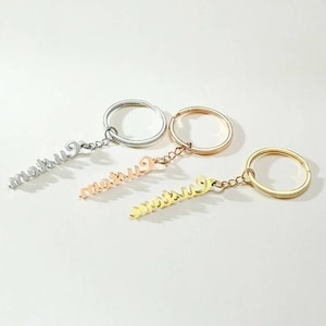May include: Three keychains with the word "custom" spelled out in cursive on each. The keychains are silver, rose gold, and gold.