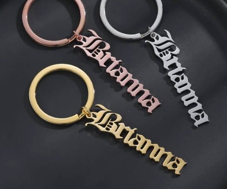 May include: Three gold, silver, and rose gold keychains with the name "Brianna" in a gothic font.