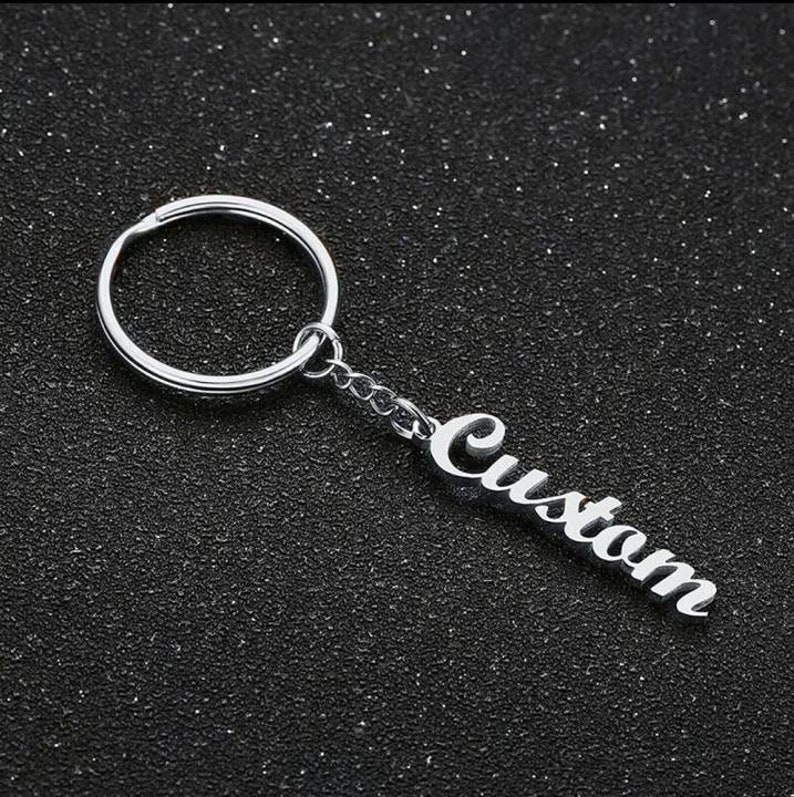 May include: Silver keychain with a silver ring and a silver charm that says "Custom".