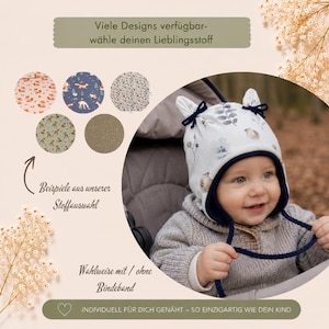 K&ouml;nnte beinhalten: Eine wei&szlig;e M&uuml;tze mit botanischem Muster, dunkelblauem Saum und zwei kleinen &ouml;hrchenartigen Spitzen oben mit dunkelblauen Bindeb&auml;ndern. Das Bild enth&auml;lt den Text: Viele Designs verf&uuml;gbar-w&auml;hle deinen Lieblingsstoff, Beispiele aus unserer Stoffauswahl, Wahlweise mit / ohne Bindeband, INDIVIDUELL F&Uuml;R DICH GEN&Auml;HT &ndash; SO EINZIGARTIG WIE DEIN KIND.