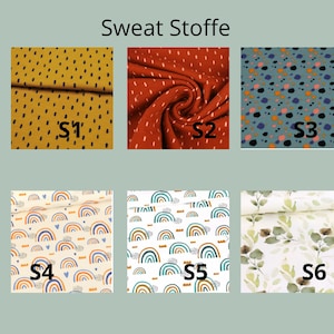 K&ouml;nnte beinhalten: Eine Sammlung von sechs Stoffmustern mit der Aufschrift Sweat Stoffe, mit Mustern wie senfgelb mit schwarzen Strichen, rostrot mit wei&szlig;en Strichen, blau mit bunten Punkten, Regenb&ouml;gen auf Creme, Regenb&ouml;gen auf Wei&szlig; und gr&uuml;nen Bl&auml;ttern.