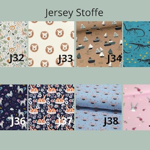 May include: A collection of eight jersey fabric swatches labeled J32 through J39, featuring patterns of giraffes, lions, boats, dinosaurs, unicorns, deer, crabs, and rabbits in various colors including blue, pink, brown, and cream.