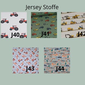 May include: Five swatches of jersey fabric labeled J40 through J44. J40 features red tractors on white. J41 shows tractors on olive green. J42 displays yellow construction vehicles on light gray. J43 has helicopters on blue. J44 shows cars on gray.