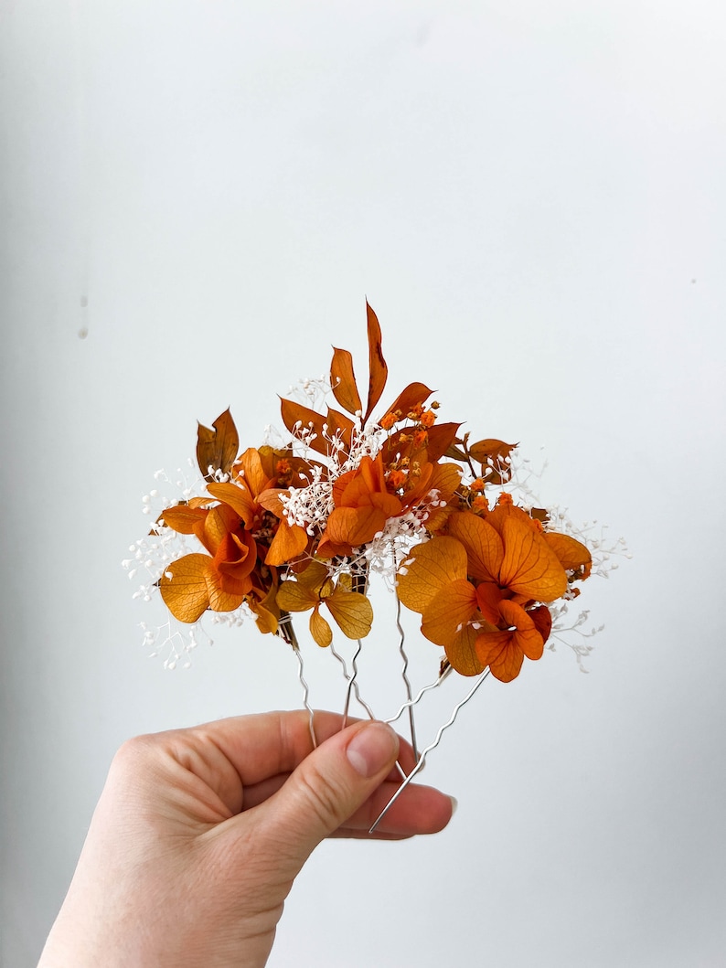 May include: Set of four hair pins with dried orange flowers and white baby's breath.