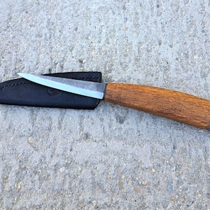 May include: A small, sharp knife with a wooden handle and a leather sheath. The blade is silver and the handle is brown.