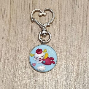 Könnte beinhalten: Eine weiße Keramik-Tasse mit schwarzem Henkel und dem Text "But First, Coffee" in schwarzer, handschriftlicher Schrift. Die Tasse steht auf einer weißen Oberfläche.