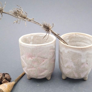 Dos pequeñas tazas de cerámica con pies
