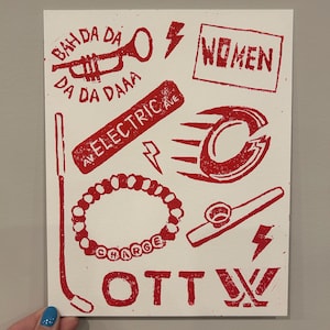 Puede incluir: Impresión roja y blanca con ilustraciones de una trompeta, rayos, la palabra "WOMEN", una pulsera con "CHARGE" y la palabra "OTT". La impresión tiene una estética estampada a mano.