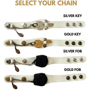 Puede incluir: Cuatro pulseras de cuero blanco con diferentes dijes. Las dos pulseras superiores tienen un dije de llave, las dos inferiores tienen un dije de llavero. La pulsera superior tiene un dije de llave plateado, la segunda pulsera tiene un dije de llave dorado, la tercera pulsera tiene un dije de llavero plateado y la pulsera inferior tiene un dije de llavero dorado. Cada pulsera tiene tres broches dorados o plateados.