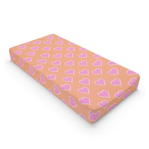 May include: Orange and pink striped fabric with a pattern of pink hearts. The fabric is folded into a rectangular shape.