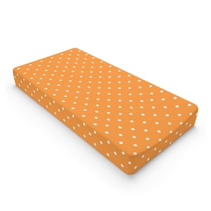 May include: Orange and white polka dot fitted crib sheet.