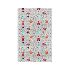 May include: A white fabric with a repeating pattern of a nutcracker, a ballerina, and a mouse. The background is a light gray with small black dots.