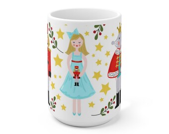 May include: White ceramic mug with a colorful illustration of a girl in a blue dress holding a nutcracker doll, a nutcracker soldier, and a mouse king. The background features gold stars and red berries.