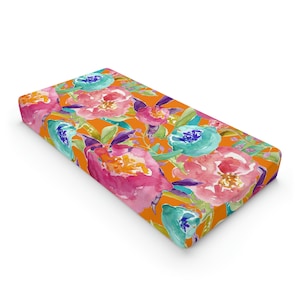May include: Orange fabric with a watercolor floral pattern featuring pink, blue, and yellow flowers.