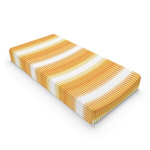 May include: A white and orange striped fitted crib sheet. The sheet has a geometric pattern of vertical stripes.