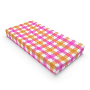 May include: A pink and orange checkered crib sheet. The sheet is made of a soft, breathable fabric and is perfect for keeping your baby comfortable and cool.