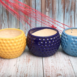 Pode incluir: Três vasos de cerâmica em amarelo, azul e azul claro. Cada vaso tem uma superfície texturizada e com reentrâncias.