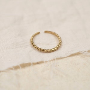Könnte beinhalten: Ein goldfarbener Ring mit einem Perlenmuster. Der Ring ist schlicht und zart.