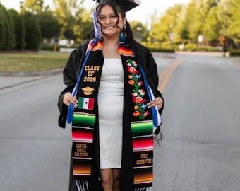 May include: A graduation stole featuring vibrant, multi-colored striped patterns with embroidered floral motifs. The stole includes text reading Class of 2026, Central Garcia San Pedro, and First Generation, along with a small Mexican flag patch.