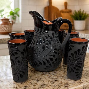 May include: A black ceramic pitcher and six matching tumblers featuring a matte finish with glossy black embossed swirl patterns and a terracotta interior. The pitcher has a curved handle and a pouring spout, while the tumblers are cylindrical.