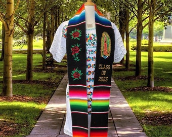 May include: Black graduation stole with colorful stripes, embroidered with roses, a religious figure, and the text "CLASS OF 2023".
