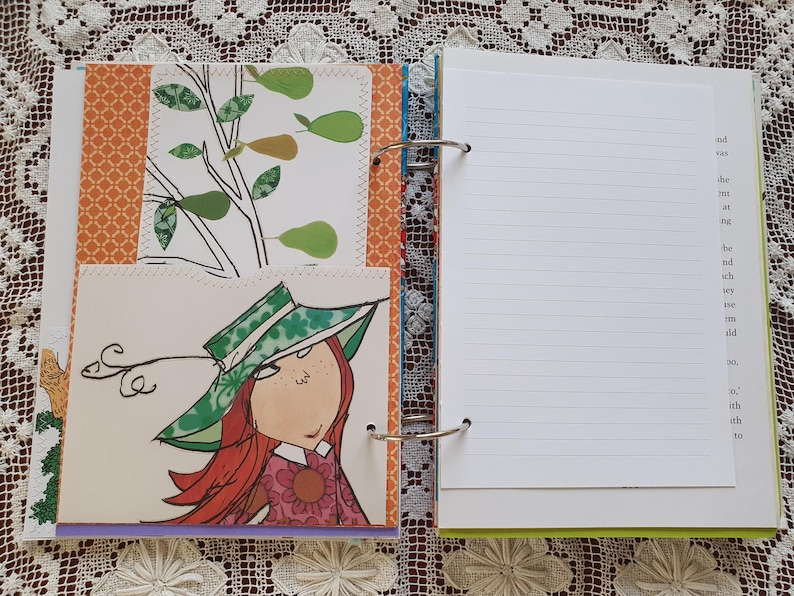 May include: A colorful binder with a white page open, showing lined paper. The binder has a green, blue, and orange design. The page has handwritten text on the right side.