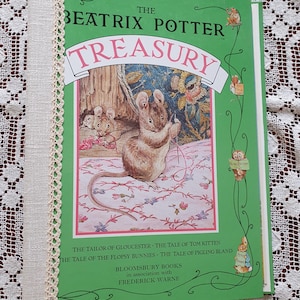 Può includere: Un libro con copertina rigida verde, "The Beatrix Potter Treasury", con dorso in pizzo color crema. La copertina presenta illustrazioni di topi e un motivo floreale rosa. Il libro include storie come "The Tailor of Gloucester".