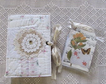 May include: A handmade journal with a white fabric cover decorated with lace and doilies. The journal is tied with a white ribbon and comes with a set of tags featuring a floral design and a butterfly.