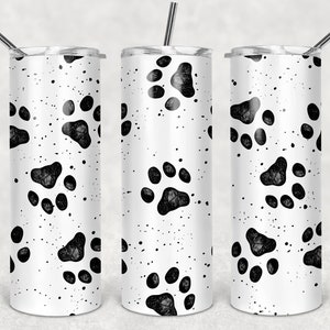 May include: Three stainless steel tumblers with black paw print designs on a white background. The tumblers have lids and straws.