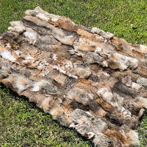 Op de afbeelding: Een patchwork-kleed gemaakt van meerdere stukken bruine, bruine en witte dierenvacht. De vacht is in een rechthoekige vorm gerangschikt en lijkt van verschillende diersoorten te komen.