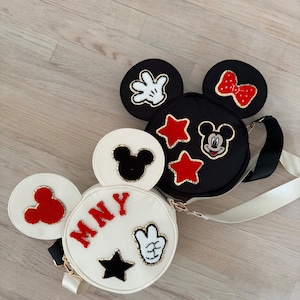 May include: Two black and white Mickey Mouse-shaped purses with red, black, and white embellishments. One purse has the name "MNY" on it.