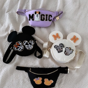 May include: Four different Disney-themed bags. A purple fanny pack with the word "MAGIC" and a Mickey Mouse ghost. A black round bag with Mickey Mouse and Minnie Mouse ears. A white round bag with Mickey Mouse ears and Mickey Mouse and Minnie Mouse characters. A black fanny pack with two Mickey Mouse characters.