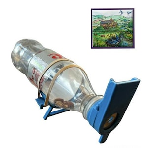 May include: A clear plastic bottle with a blue plastic attachment and a rubber band. The bottle is held in place by a blue stand. A small framed painting of a landscape is in the background.