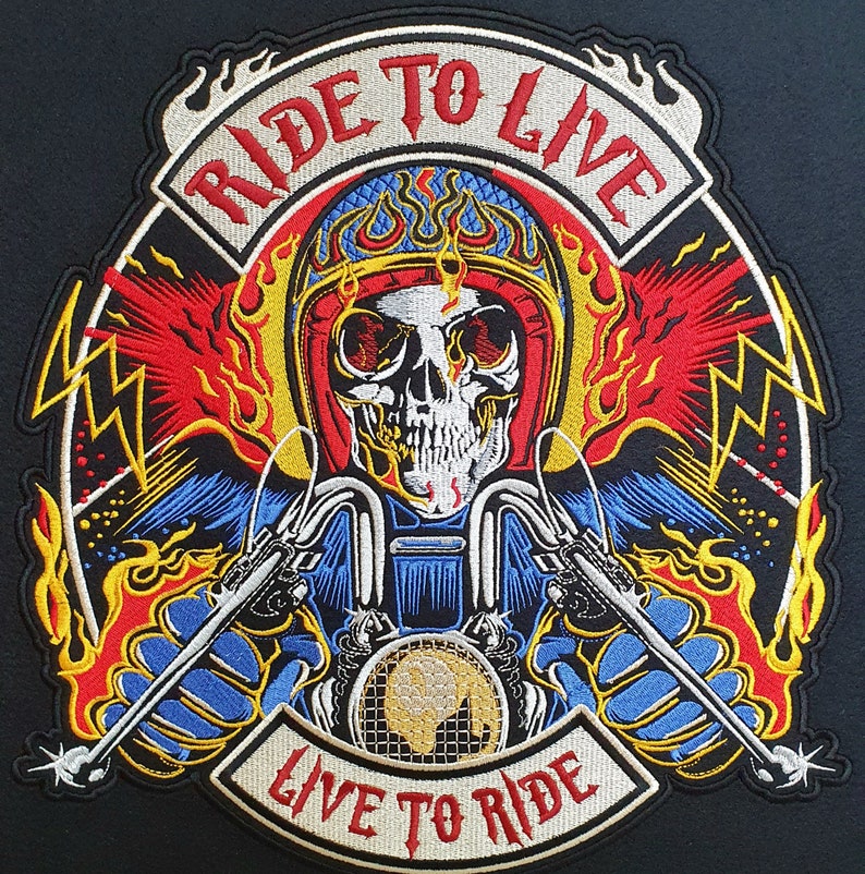 May include: Embroidered patch featuring a skull wearing a flaming helmet, riding a motorcycle. The patch has the text "RIDE TO LIVE" above and "LIVE TO RIDE" below. The design incorporates red, yellow, blue, and white colors.