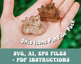May include: Two wooden pin designs featuring a bird and a leafy branch with the word "OHIO" on a banner. The pins are held in a hand against a green background. The text "Ohio Icons Pin File Pack" is written in a curved font on the image. The text "SVG, AI, EPS FILES + PDF INSTRUCTIONS" is written in a large, bold font at the bottom of the image.