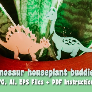 May include: Two pink and blue dinosaur houseplant buddies made of acrylic. The dinosaurs are standing in a red pot with a green plant. The image includes the text "dinosaur houseplant buddies" and "SVG, AI, EPS Files + PDF Instructions".