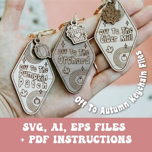 May include: Three wooden keychains with a retro motel sign design. Each keychain features a different autumn theme: "Off to the Pumpkin Patch", "Off to the Orchard", and "Off to the Cider Mill".