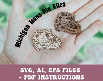 May include: Two wooden laser cut pins featuring a bird with flowers and the word "MICHIGAN" on a banner. The pins are in a person's hand. The image includes the text "Michigan Icons Pin Files" and "SVG, AI, EPS FILES + PDF INSTRUCTIONS".